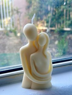 a small white statue sitting on top of a window sill next to a window