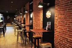 the interior of a restaurant with brick walls and bar stools lined up against the wall