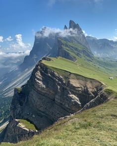 the mountain is high up in the sky with clouds and grass on it's sides