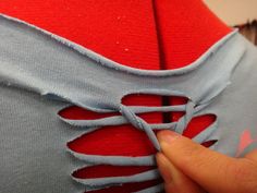 someone is stitching out the side of a sports jersey with red and grey strips