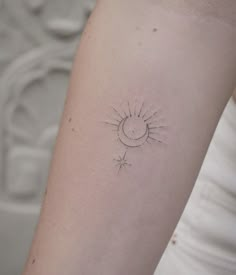 a small sun and moon tattoo on the left inner arm, which is drawn in white ink