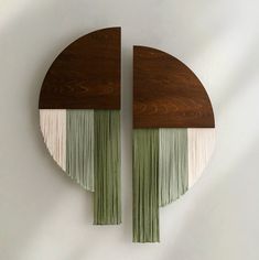 two circular wooden wall hangings with green and white tassels on each side