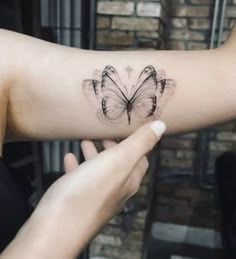 a woman's arm with a butterfly tattoo on the left side of her arm