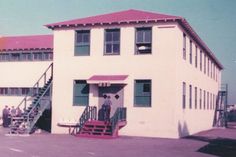 an old building with stairs leading to it and people standing outside the door on either side