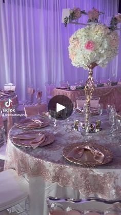 the table is set with pink and white flowers, silverware, and gold plates