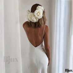 the back of a woman wearing a white dress with flowers on her head and shoulders