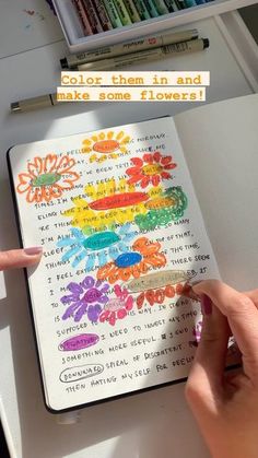 someone is drawing on a notebook with colored crayons