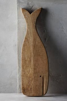 a wooden cutting board sitting on top of a counter next to a knife holder and wall