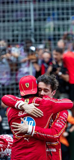 two men in red racing suits hugging each other