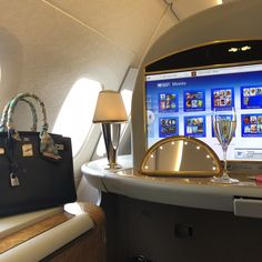 a laptop computer sitting on top of an airplane seat next to a purse and lamp