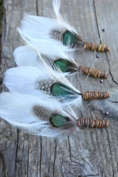 three white feathers are lined up on a piece of wood with bead and beads