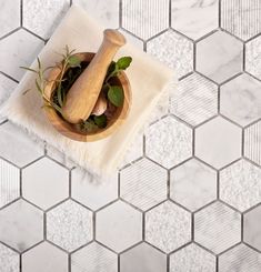 a wooden mortar and pestle in a bowl on a white marble tile floor with hexagonal tiles