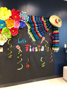 a blackboard with colorful paper flowers on it and the words let's fiesta