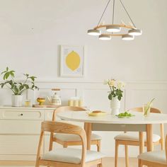 a dining room table with four chairs around it and flowers in vases on the table