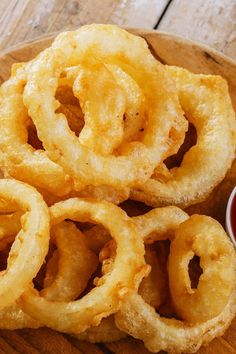 some onion rings on a wooden plate with ketchup