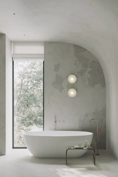 a large white bath tub sitting in a bathroom next to a window with two lights on it