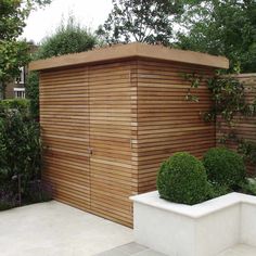 a wooden structure in the middle of a garden with two white planters next to it