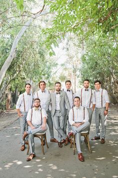 a group of men standing next to each other on top of a wooden chair in front of trees