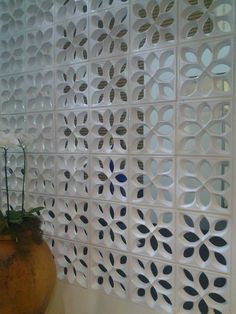 a vase filled with flowers sitting next to a white wall covered in decorative cut outs