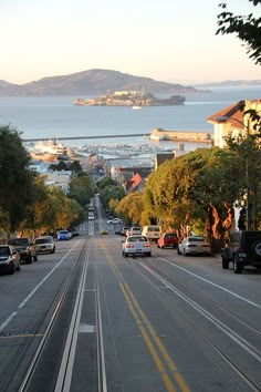 a street with cars parked on the side and some hills in the backgroud