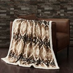 a couch with a blanket on top of it in front of a brick wall and wooden floor