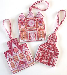 three red and white ornaments hanging from a string on a white surface with a pink ribbon