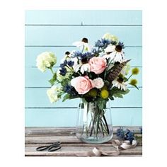 a vase filled with lots of flowers on top of a wooden table next to scissors