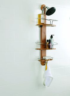 a bathroom with white tile and wooden shelves on the wall next to a shower head