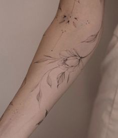 a woman's arm with flowers on it and leaves in the middle of her arm