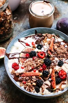 a bowl filled with yogurt, berries and granola next to some fruit