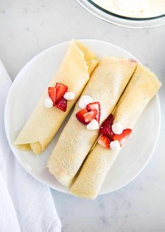 two crepes with strawberries and cream on them are sitting on a plate