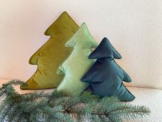 three green and blue pillows sitting on top of a white shelf next to a pine tree