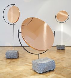 three metal sculptures on stands in an art gallery