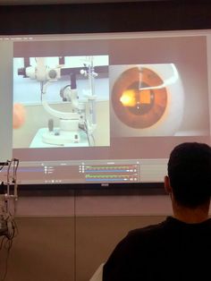 a man standing in front of a projector screen with an image of a microscope on it