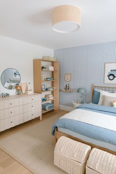 a bedroom with a bed, dresser and mirror in the corner on the wall next to it