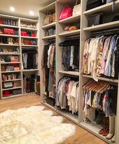 an organized closet with lots of clothes and handbags on the shelves in front of it