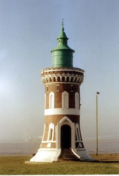 a tall tower with a green top sitting in the grass