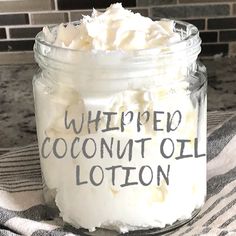 whipped coconut oil lotion in a glass jar on a kitchen counter with a striped towel