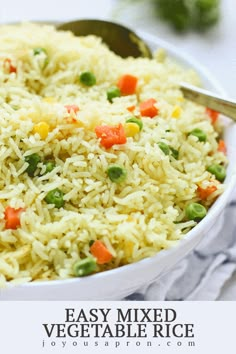 a bowl filled with rice and vegetables on top of a table next to a spoon