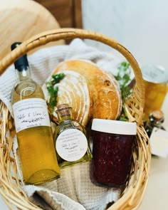 a basket filled with bread and jams on top of a white tablecloth next to a bottle of wine