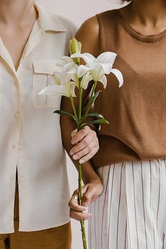 two women holding white flowers in their hands