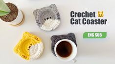 crochet cat coasters are sitting next to a cup of coffee