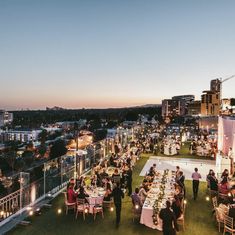 a group of people sitting at tables on top of a roof next to tall buildings