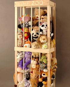 a wooden rack filled with stuffed animals on top of a floor next to a wall