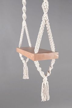 a wooden shelf with white rope hanging from it