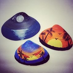 three painted rocks sitting on top of a white table next to each other with palm trees