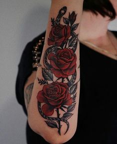 a woman with a tattoo on her arm holding onto a red rose and an arrow