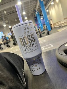 a travel cup sitting on top of a table next to a black bag at an airport