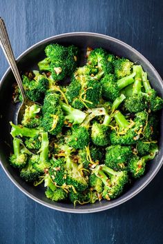 a bowl filled with broccoli on top of a blue tablecloth next to a spoon