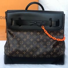 *Brand New* Limited Edition. From The Spring/Summer 2019 Collection. Men's Brown And Tan Monogram Coated Canvas Louis Vuitton Monogram Steamer Pm With Black Coated Hardware, Single Rolled Top Handle, Optional Flat Shoulder Strap Featuring Peg-In-Hole Adjustment, Black Leather Trim, Single Zip Pocket At Back, Black Canvas Lining, Three Interior Slit Pockets And Matte Orange Resin Chain Accented Peg-In-Hole Closure Featuring Dual Pull-Through Buckle Closures At Front Flap. Includes Dust Bag. Orange Resin, Resin Chain, Pull Through, Summer 2019, Black Canvas, Leather Trim, Black Coat, Leather Trims, Louis Vuitton Bag